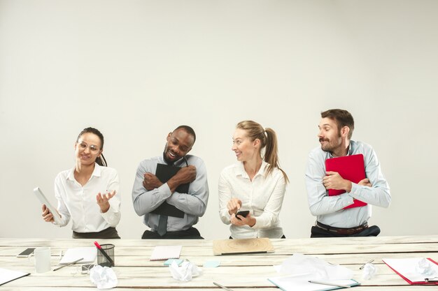 Jóvenes africanos y caucásicos hombres y mujeres sentados en la oficina y trabajando en computadoras portátiles.