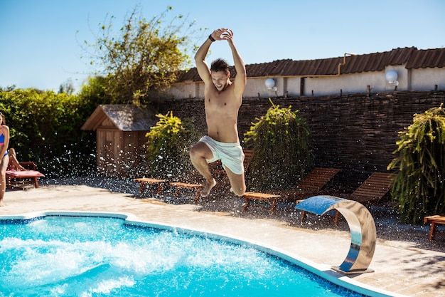 Jóvenes alegres amigos sonriendo, relajándose, saltando en la piscina