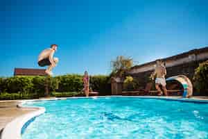 Foto gratuita jóvenes alegres amigos sonriendo, relajándose, saltando en la piscina