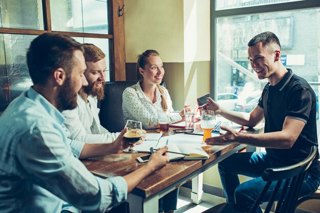 Jóvenes alegres sonrientes y relajantes en pub.