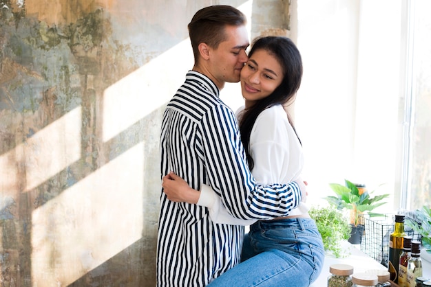 Jóvenes amantes felices abrazándose suavemente en la cocina