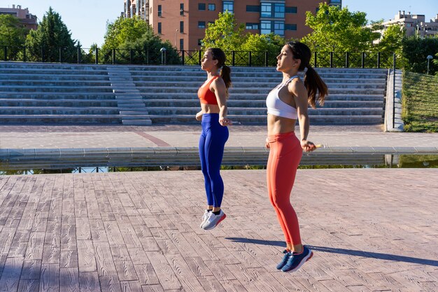 Jóvenes amigas caucásicas haciendo ejercicios y saltando fuera