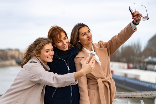 jóvenes amigas hermosas viajan, toman selfie en el teléfono inteligente, se ríen. París. El concepto de una foto de viaje feliz. Jóvenes felices tomando selfies en la ciudad