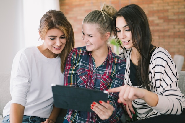 Foto gratuita jóvenes amigas mirando tableta juntos