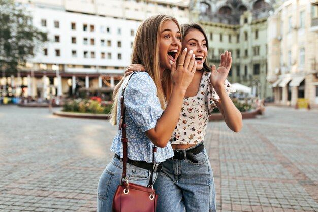 Las jóvenes amigas sorprendidas miran hacia otro lado y cubren la boca con las manos