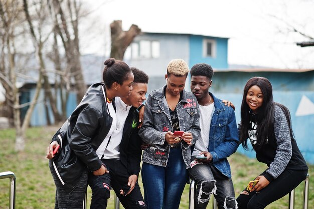 Jóvenes amigos africanos de la generación del milenio con teléfonos móviles Gente negra feliz divirtiéndose juntos Concepto de amistad de la Generación Z