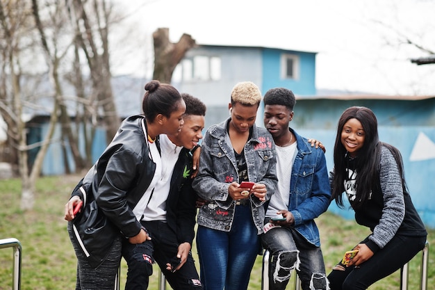 Jóvenes amigos africanos de la generación del milenio con teléfonos móviles Gente negra feliz divirtiéndose juntos Concepto de amistad de la Generación Z