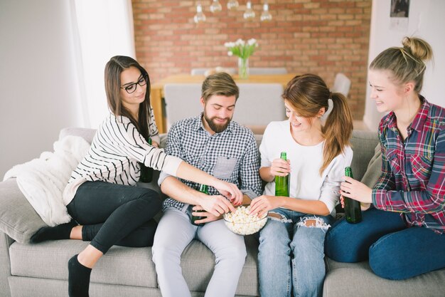 Jóvenes amigos disfrutando de cerveza y palomitas de maíz