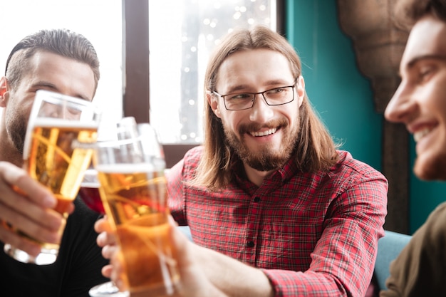 Jóvenes amigos felices sentados en la cafetería mientras bebe alcohol.