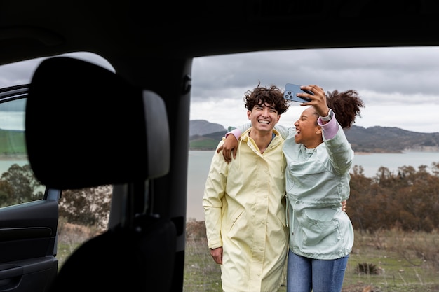 Jóvenes amigos haciéndose un selfie en un viaje familiar en coche