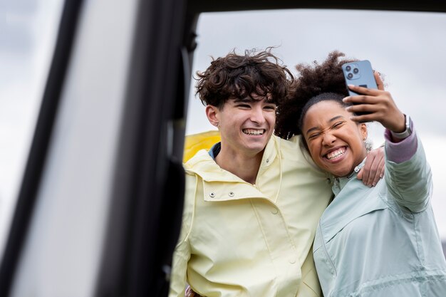 Jóvenes amigos haciéndose un selfie en un viaje familiar en coche