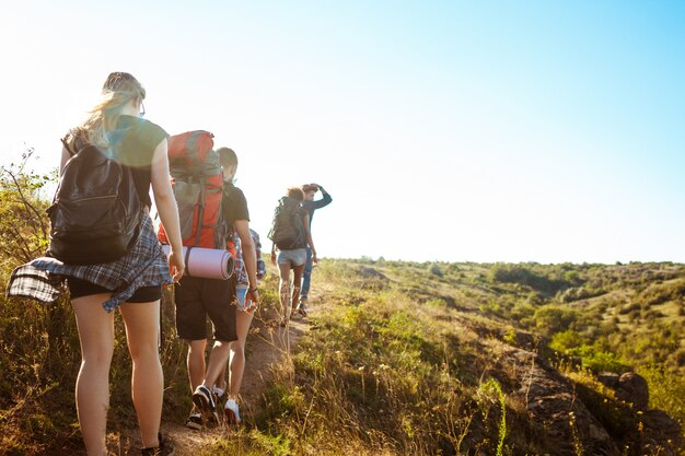 Jóvenes amigos hermosos viajeros con mochilas caminando en el cañón