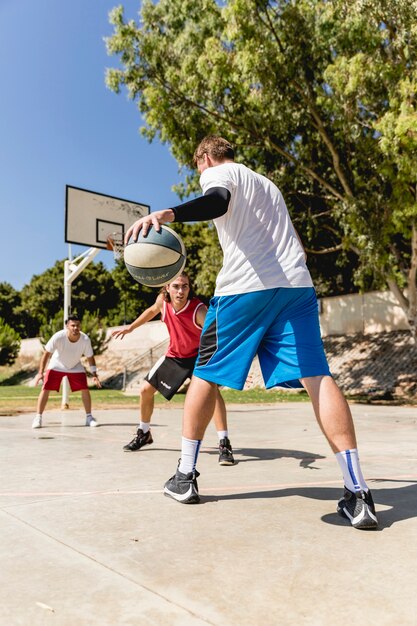 Jóvenes amigos jugando al baloncesto en la cancha al aire libre