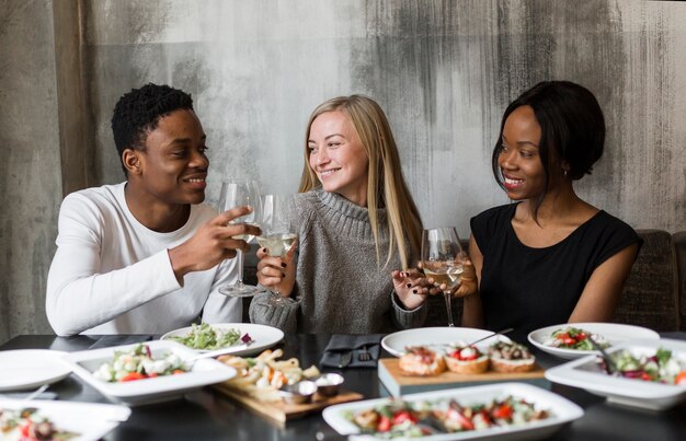 Jóvenes amigos positivos tomando vino en la cena