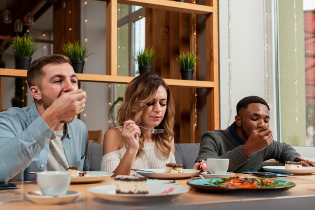 Jóvenes amigos en el restaurante comiendo