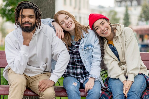 Jóvenes amigos sentados al aire libre en el banco