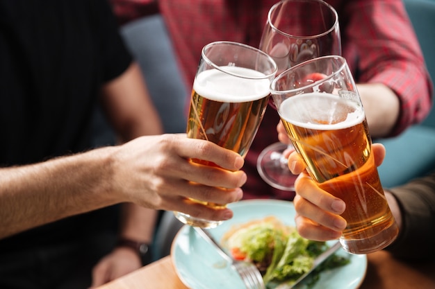 Jóvenes amigos sentados en la cafetería mientras bebe alcohol.