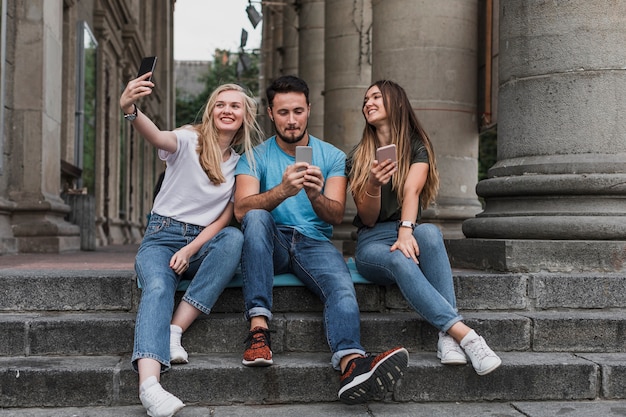 Jóvenes amigos sentados en las escaleras y tomando una selfie