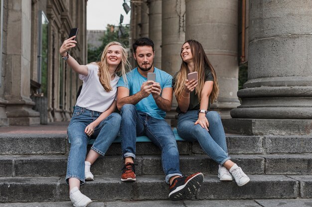 Jóvenes amigos sentados en las escaleras y tomando una selfie