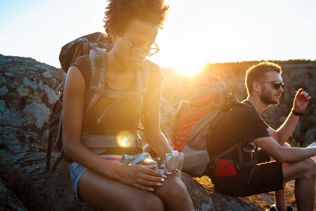 Jóvenes amigos sentados en roca en el cañón, mirando la brújula