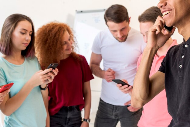 Jóvenes amigos utilizando teléfonos inteligentes para la comunicación.