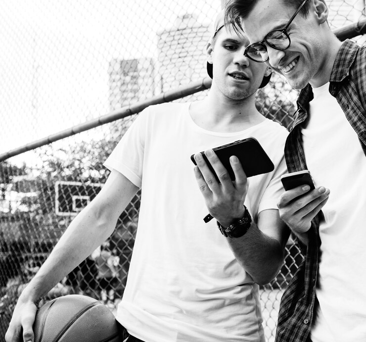 Foto gratuito jóvenes amigos varones adultos en la cancha de baloncesto con teléfonos inteligentes concepto millennials