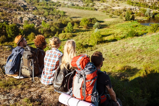 Jóvenes amigos viajeros sentados en roca en el cañón, disfrutando de la vista