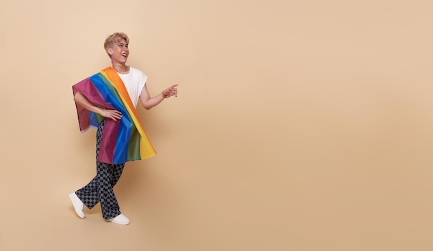 Jóvenes asiáticos transgénero LGBT con bandera del arco iris en el hombro aislado sobre fondo de color nude