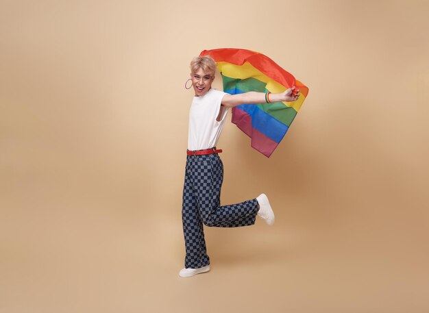 Jóvenes asiáticos transgénero LGBT mostrando la bandera del arco iris aislada sobre fondo de color nude