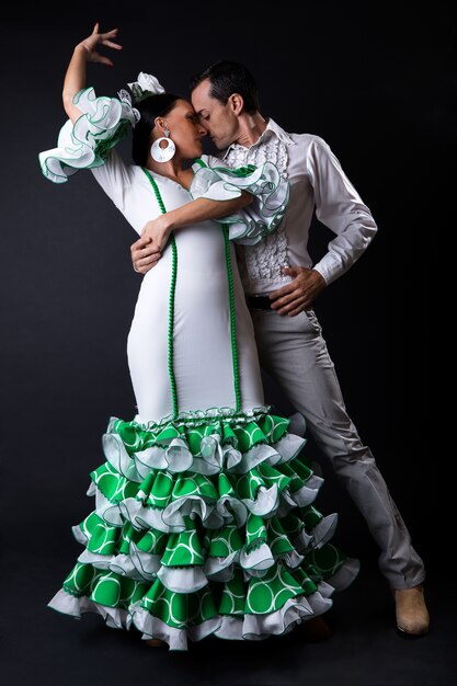 Jóvenes bailarines de flamenco en hermoso vestido sobre fondo negro.