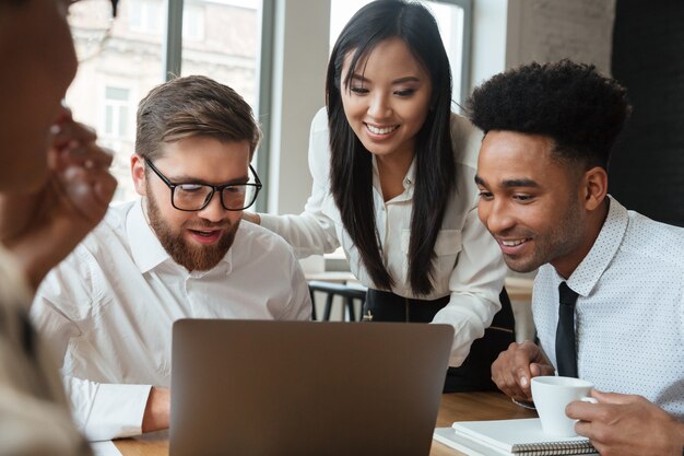 Jóvenes colegas de negocios feliz usando la computadora portátil.