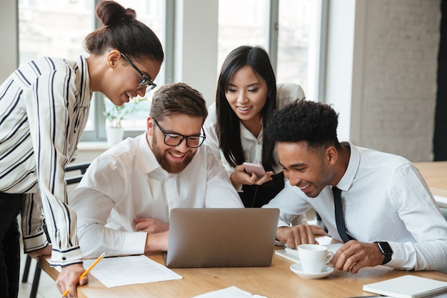 Jóvenes colegas de negocios feliz usando la computadora portátil.