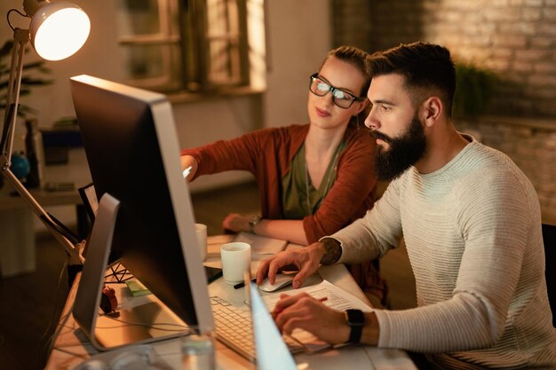 Jóvenes colegas de negocios que usan computadoras mientras trabajan juntos en la oficina