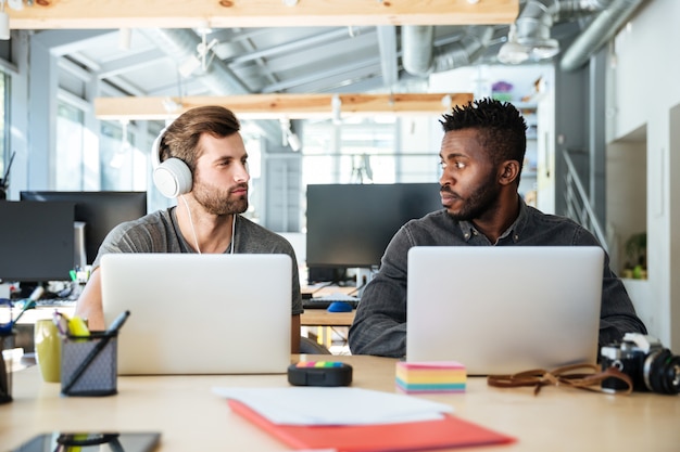 Jóvenes colegas serios sentado en la oficina de coworking