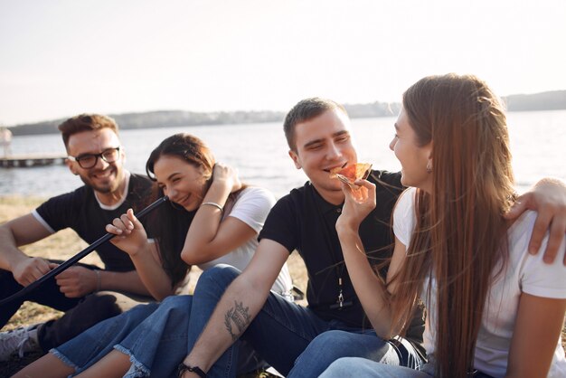 Jóvenes comiendo pizza y fumando shisha en la playa