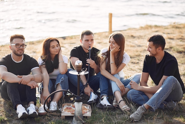 Jóvenes comiendo pizza y fumando shisha en la playa