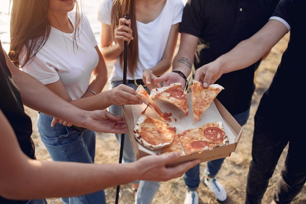 Foto gratuita jóvenes comiendo pizza y fumando shisha en la playa