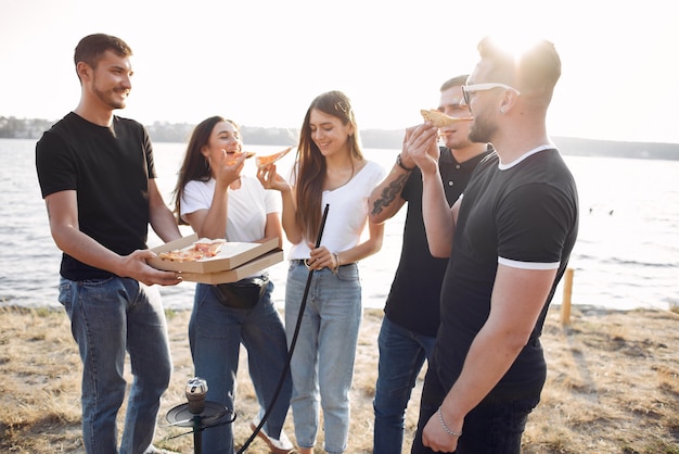 Jóvenes comiendo pizza y fumando shisha en la playa