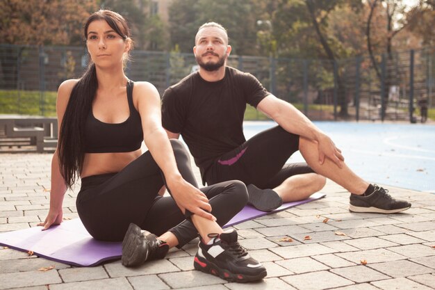 Jóvenes deportistas en colchoneta haciendo posición de yoga