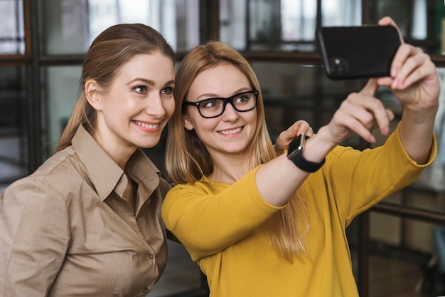 Foto gratuita jóvenes empresarias tomando un selfie juntos