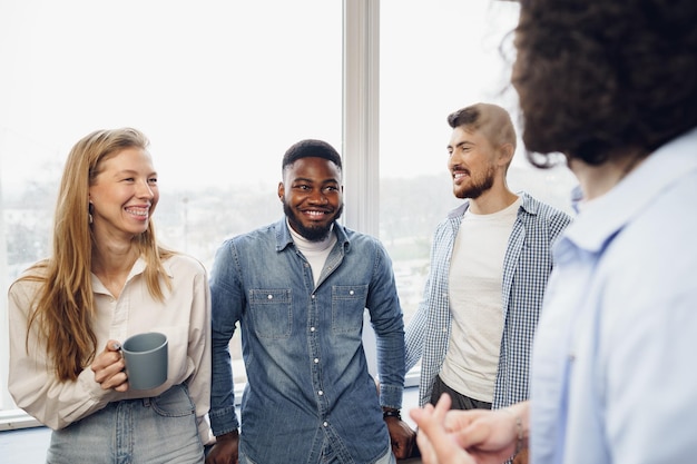 Los jóvenes empresarios alegres tienen una charla durante la pausa para el café en la oficina