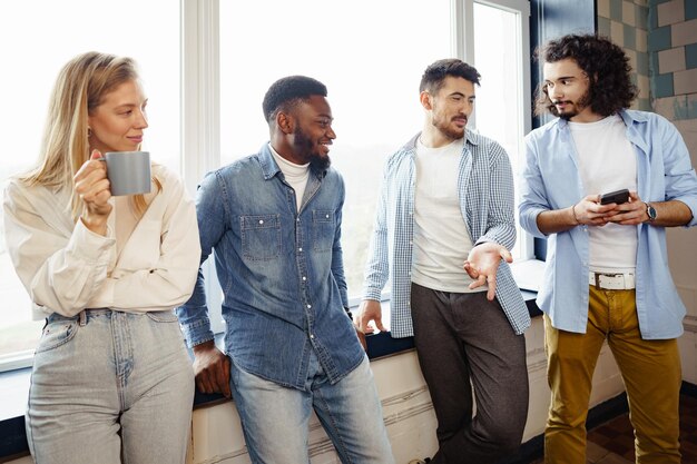 Los jóvenes empresarios alegres tienen una charla durante la pausa para el café en la oficina