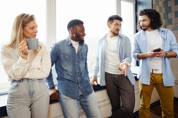 Los jóvenes empresarios alegres tienen una charla durante la pausa para el café en la oficina