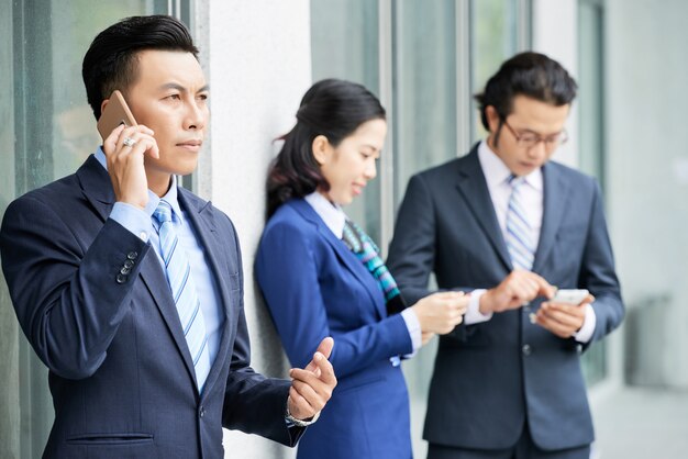 Jóvenes empresarios con teléfonos inteligentes al aire libre