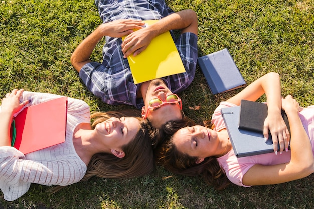 Jóvenes estudiantes con libros posando en la hierba
