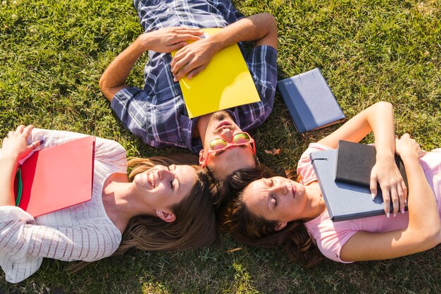 Jóvenes estudiantes con libros posando en la hierba