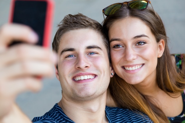 Jóvenes estudiantes tomar fotos con un teléfono inteligente en la calle.