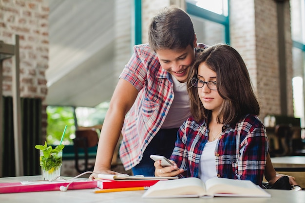 Foto gratuita jóvenes estudiantes viendo smartphone