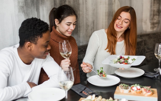 Jóvenes felices cenando y vino juntos