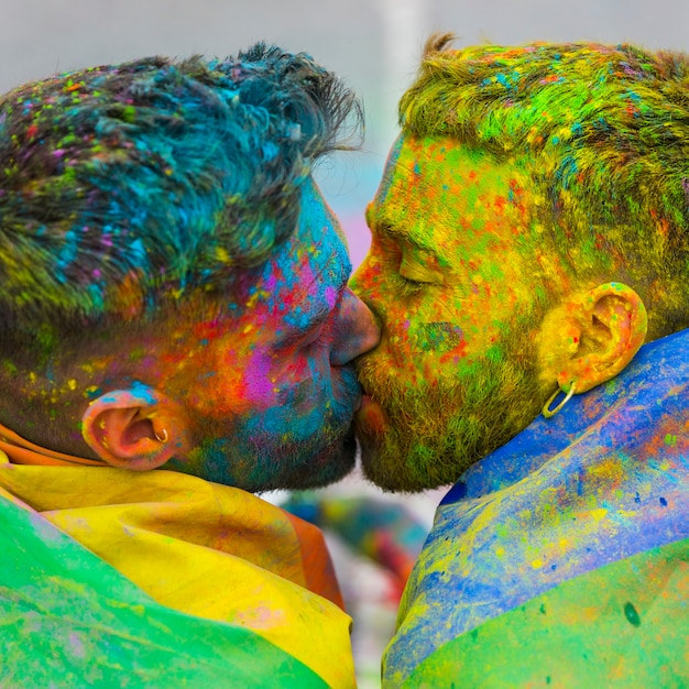 Foto gratuita jóvenes gays besándose en festival de colores holi